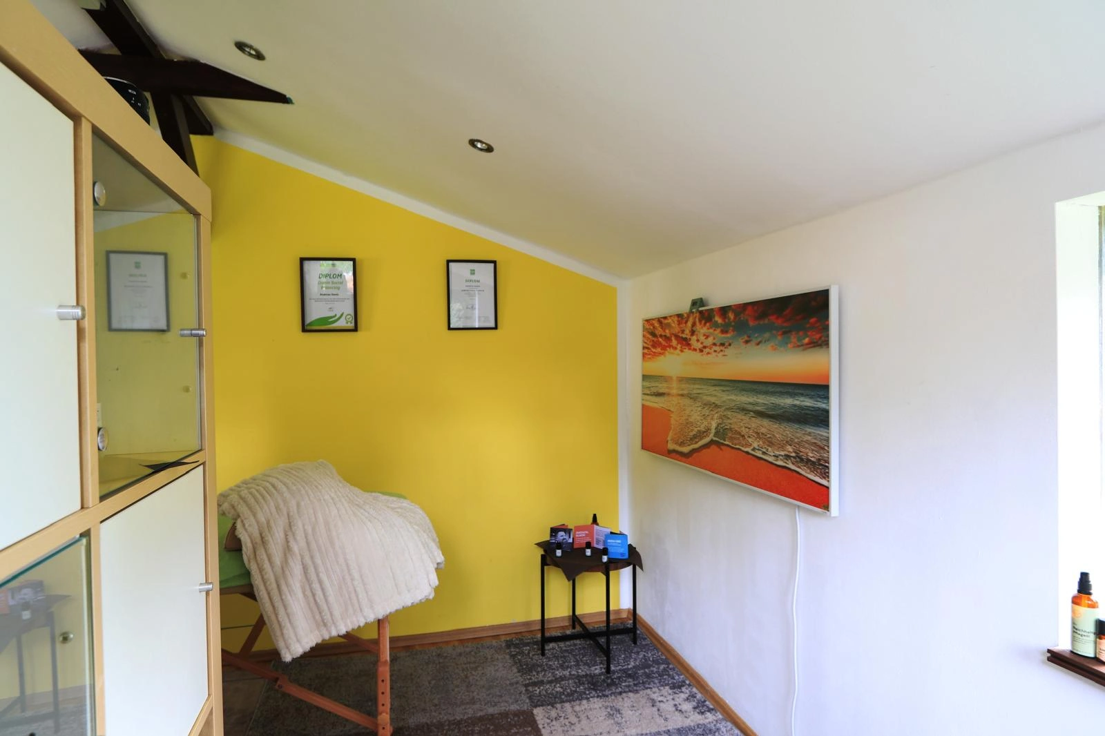 Ruhige Ecke der Praxis mit gelber Wand und einem Bild vom Meer
